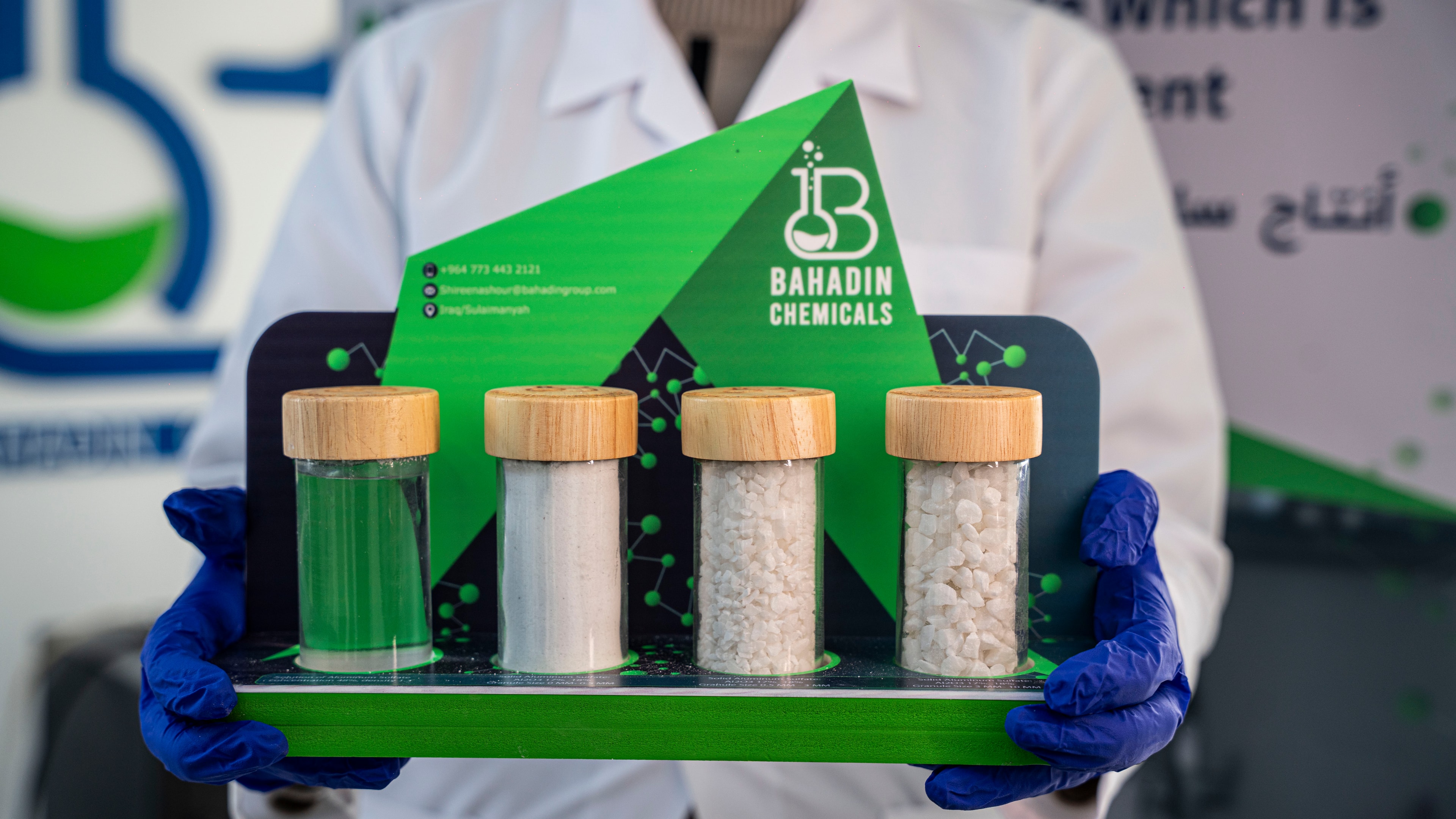 A Bahadin Chemicals display of four product jars, held in gloved hands